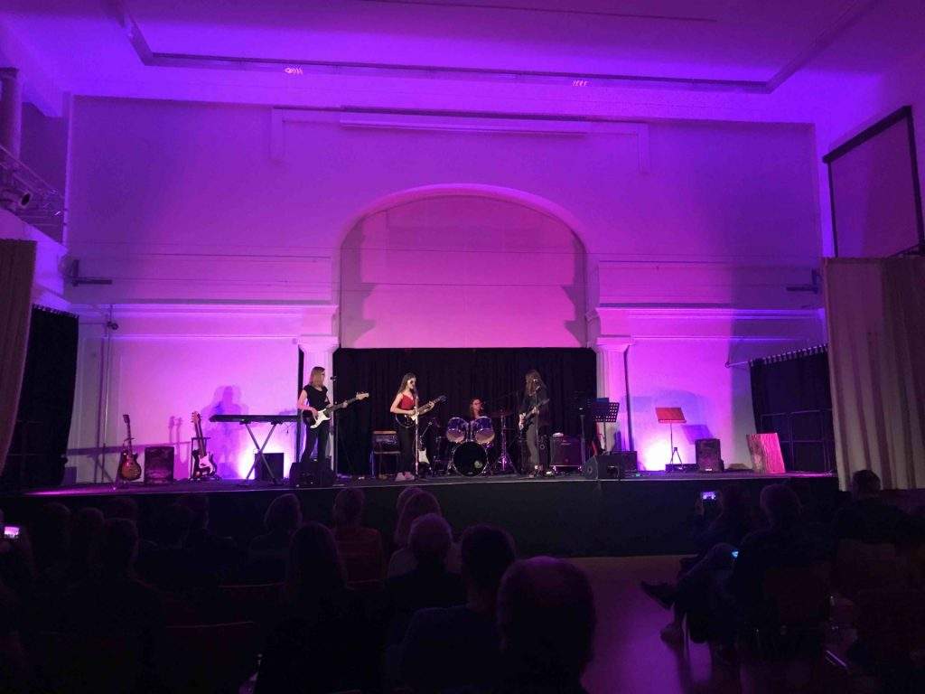 Die Jugendband Neverland spielt auf der lila erleuchteten Aula-Bühne.