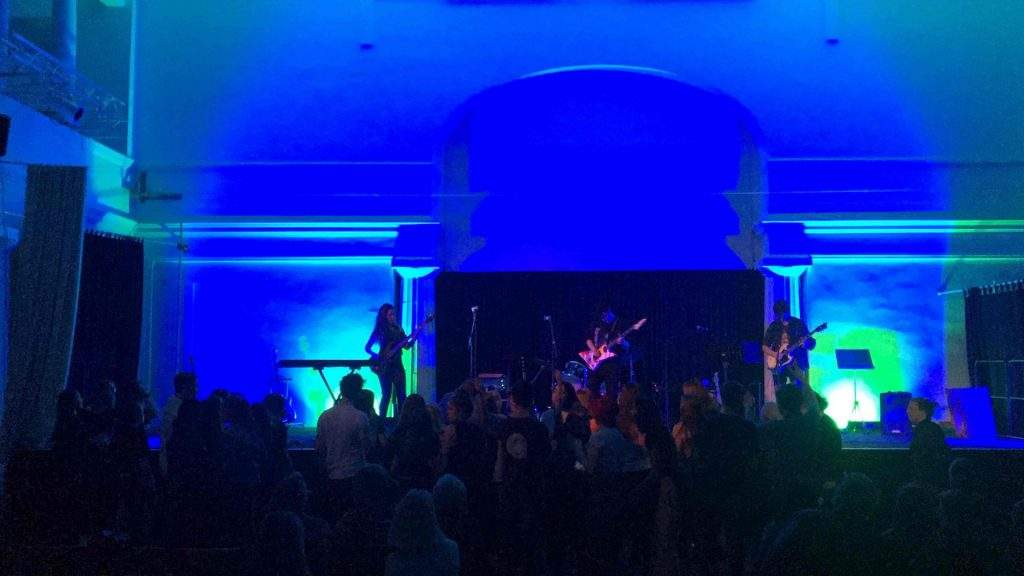 Die Jugendband The Unknown spielt auf der blau beleuchteten Aula-Bühne.