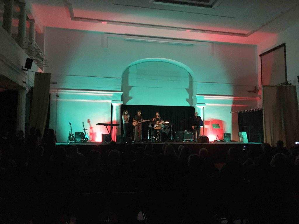 Die Jugendbahn UnderCover spielt auf der türkis und rot beleuchteten Aula-Bühne.