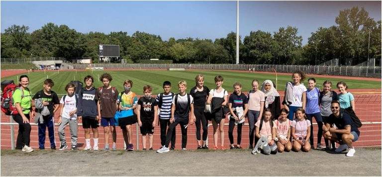 20 Schülerinnen und Schüler unserer Schule stehen vor dem Wettkampf am Rand der Tartanbahn zum Gruppenfoto.
