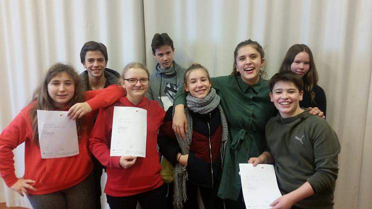8 Jungen und Mädchen, die seitens der FEO am Wettbewerb "Jugend debattiert" teilnahmen schauen lachend in die Kamera. Einige halten Zertifikate in der Hand.