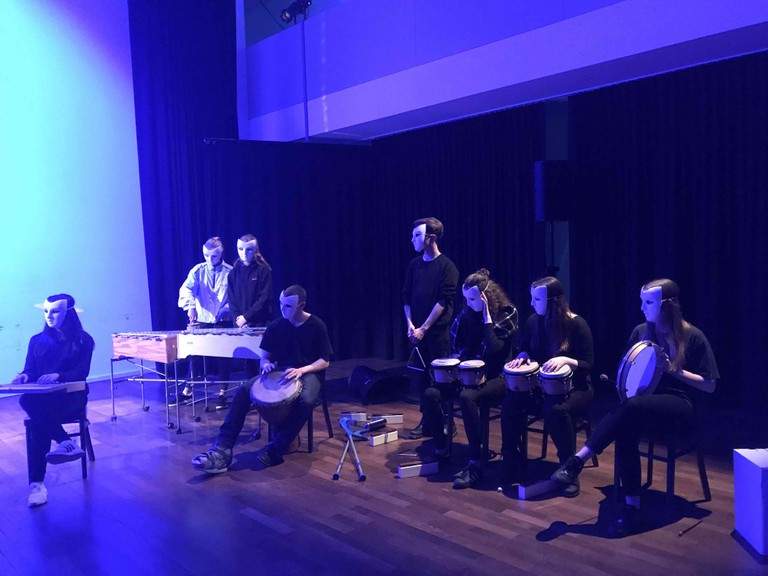 Die Trommler des Ensembles musizieren im blauen Scheinwerferlicht.