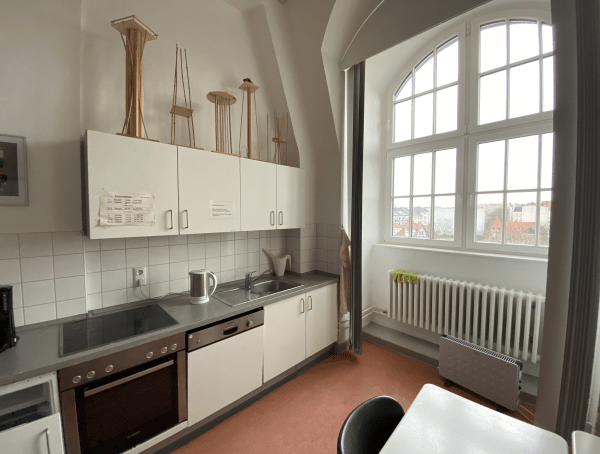 Moderne Küchenzeile mit Herd, Spülmaschine, Wasserkocher und Kühlschrank.