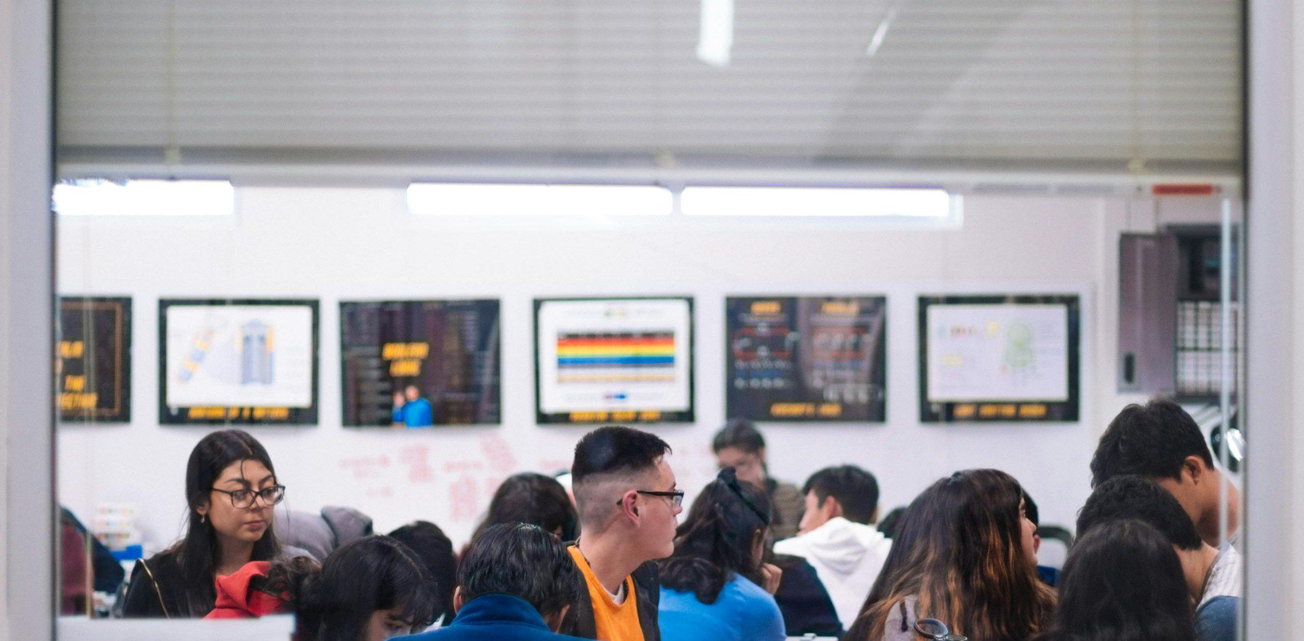 High school students actively learning in a well-lit classroom setting with educational posters.